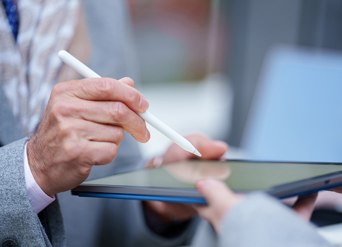 Nahaufnahme einer Person, die auf einem Tablet unterschreibt, das von einer anderen Person gehalten wird