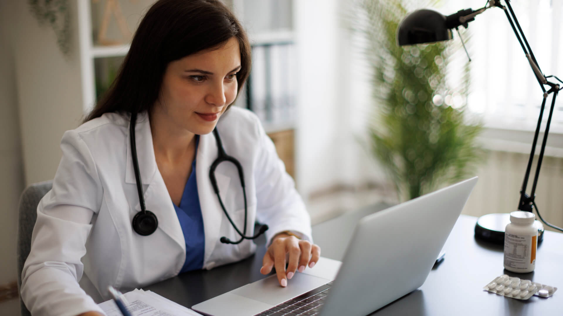 Doctor looks at laptop and smiles.