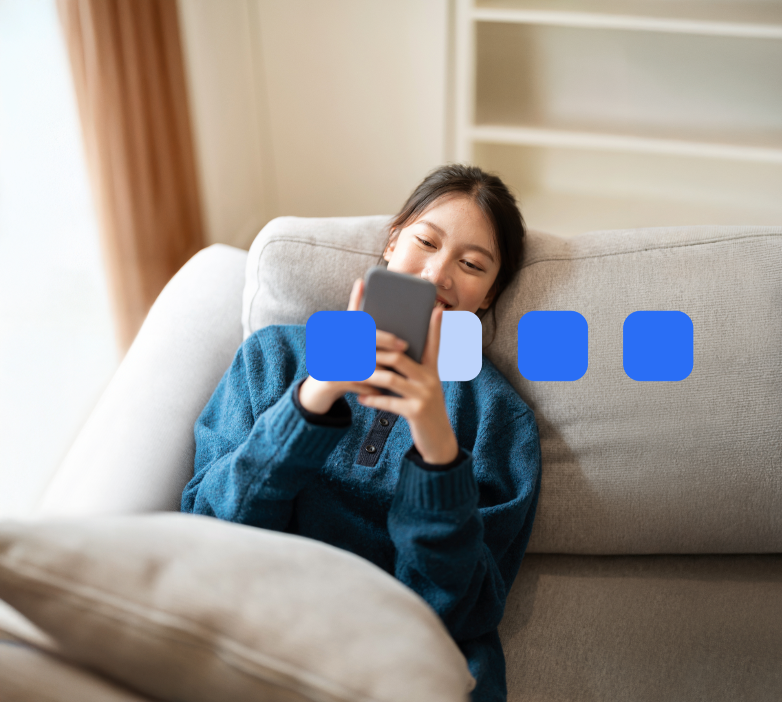 Frau liegt auf dem Sofa und schaut aufs Handy.