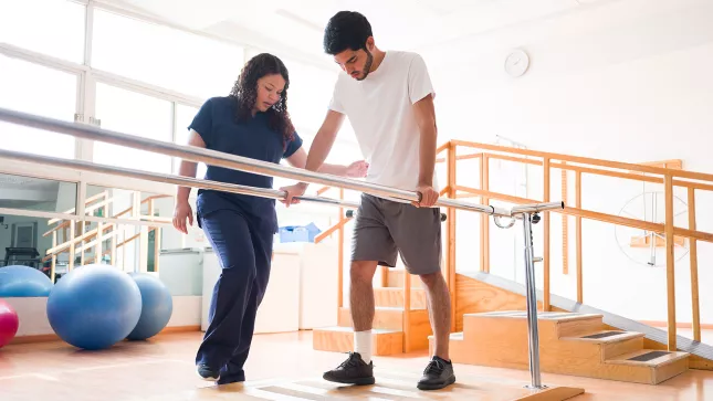 Foto einer Physiotherapeutin, die einen männlichen Patienten in einer Physiotherapie-Praxis behandelt