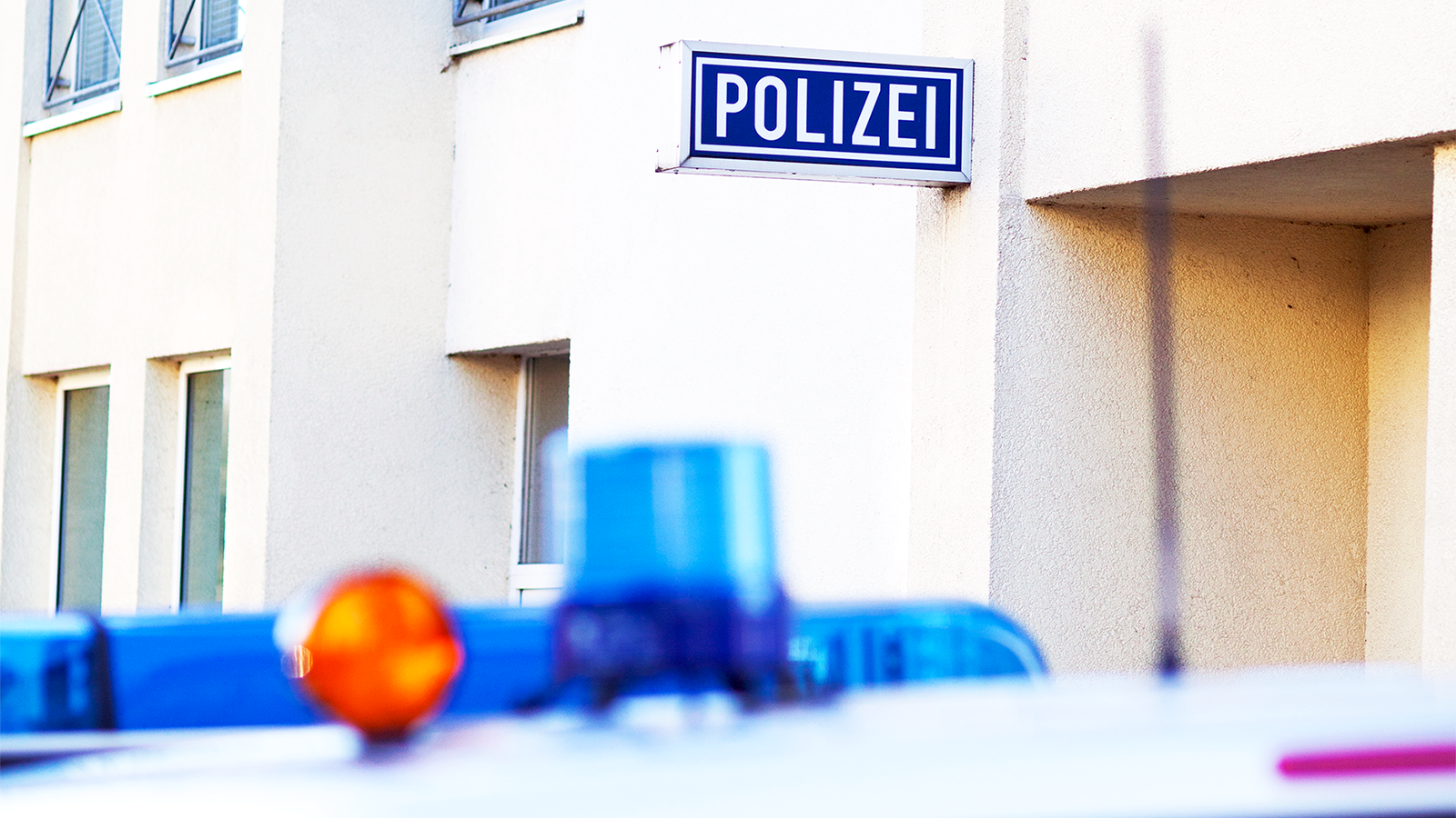 Foto des Eingangs einer Polizeiwache. Im Vordergrund ist ein Polizeiauto zu sehen.