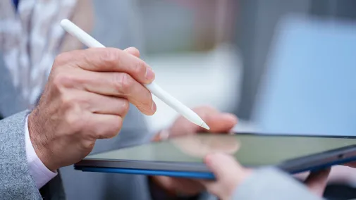Nahaufnahme einer Person, die auf einem Tablet unterschreibt, das von einer anderen Person gehalten wird