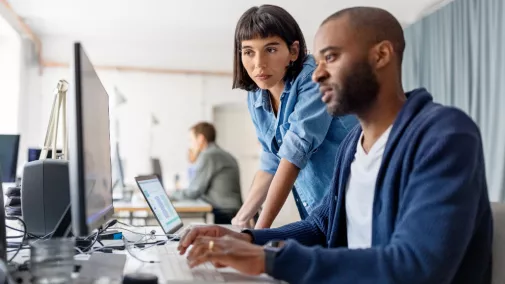 Eine Frau und ein Mann schauen auf ein Computer.