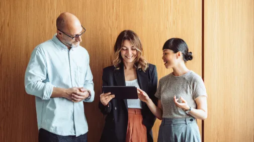 Drei Personen stehen und sprechen miteinander.