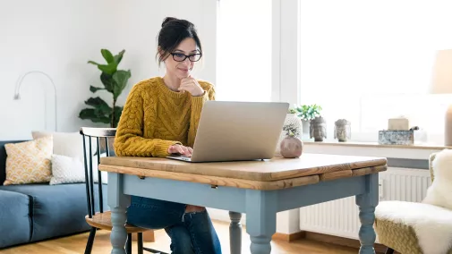 Eine Frau sitzt vor einem Computer und arbeitet zu Hause. Eine Frau sitzt vor einem Computer und arbeitet zu Hause.