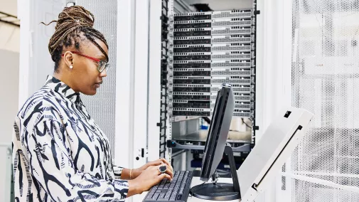 Eine Frau sitzt am Computer. Eine Frau sitzt am Computer und arbeitet am Server.