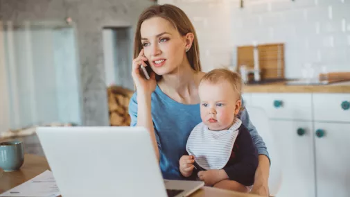 Frau sitzt mit Kind am Computer mit Handy zu Hause Frau sitzt mit Kind am Computer mit Handy zu Hause