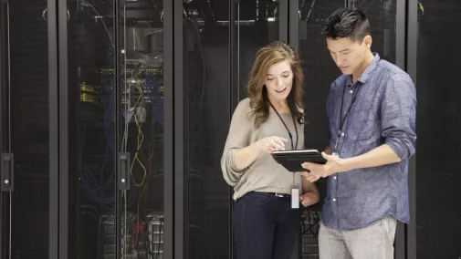 Frau und Mann stehen mit Tablet vor einem Server Frau und Mann stehen mit Tablet vor einem Server