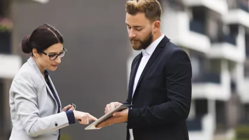 Frau und Mann mit Tablet draussen Unterschrift Frau und Mann mit Tablet draussen Unterschrift