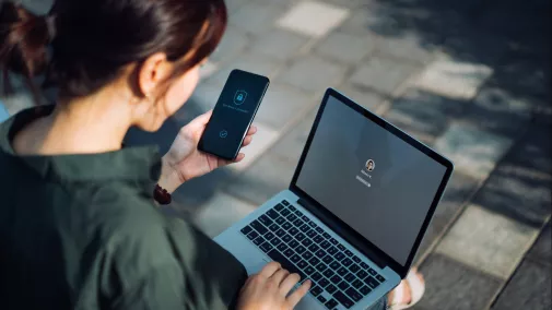 Frau versucht sich mit Smartphone für Notebook zu authenitifizieren Frau versucht sich mit Smartphone für Notebook zu authenitifizieren