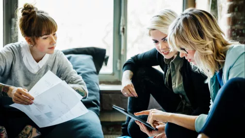 Frauen sitzen in Runde Besprechung mit Papier und Tablet im Büro Frauen sitzen in Runde Besprechung mit Papier und Tablet im Büro
