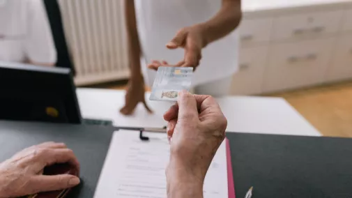 Hände überreichen Krankenkassenkarte an Arzt odr Krankenschwester in Praxis Hände überreichen Krankenkassenkarte an Arzt odr Krankenschwester in Praxis