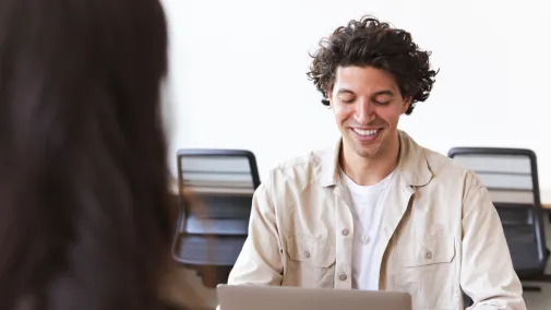 Ein Mann schaut auf seinen Laptop und lächelt.