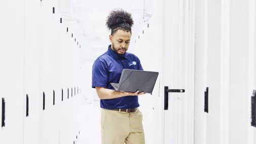 Mann mit Notebook steht im Serverraum Mann mit Notebook steht im Serverraum