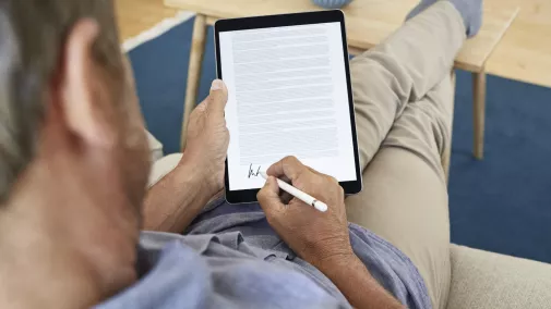 Mann mit Tablet unteschreibt digital von zu Hause Mann mit Tablet unteschreibt digital von zu Hause