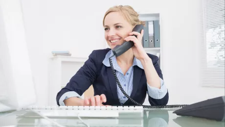 Frau am Computer mit Telefon im Büro