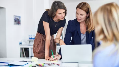 Besprechung im Büro mit drei Frauen die am Laptop arbeiten.