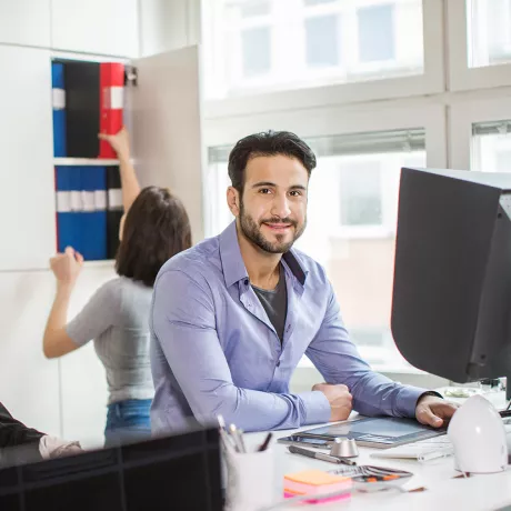 Mann und Frau sitzen am Schreibtisch im Büro.