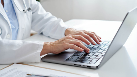 Arzt tippt auf Laptop-Tastatur