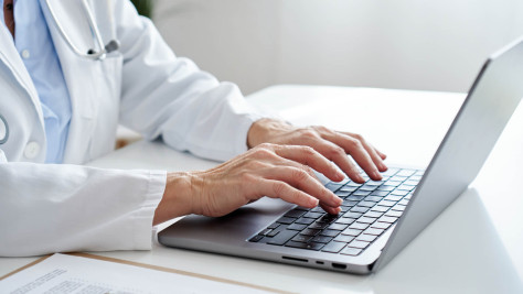Doctor typing on laptop keyboard