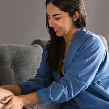 Photo of a pregnant woman lying on a couch and being examined by a midwife